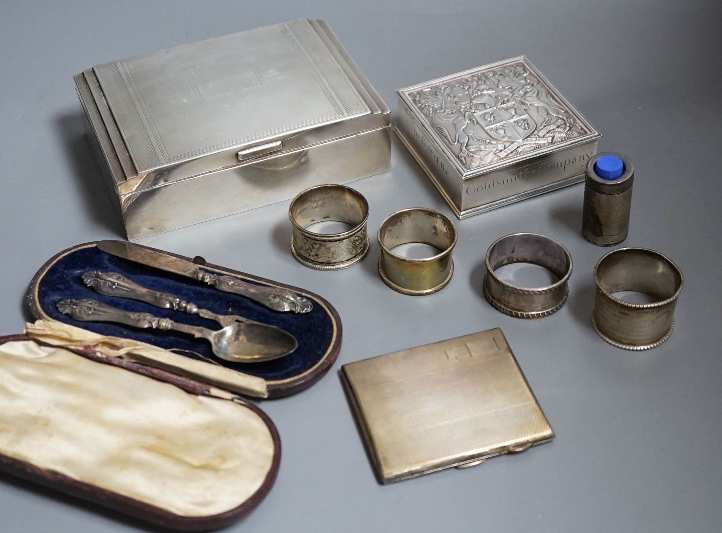 Sundry silver items including a George V 'The Gift of the Goldsmiths Company' box by Garrard & Co, London, 1926, 92mm, a silver cigarette case and box, four silver napkin rings, a cased silver christening trio and a silv